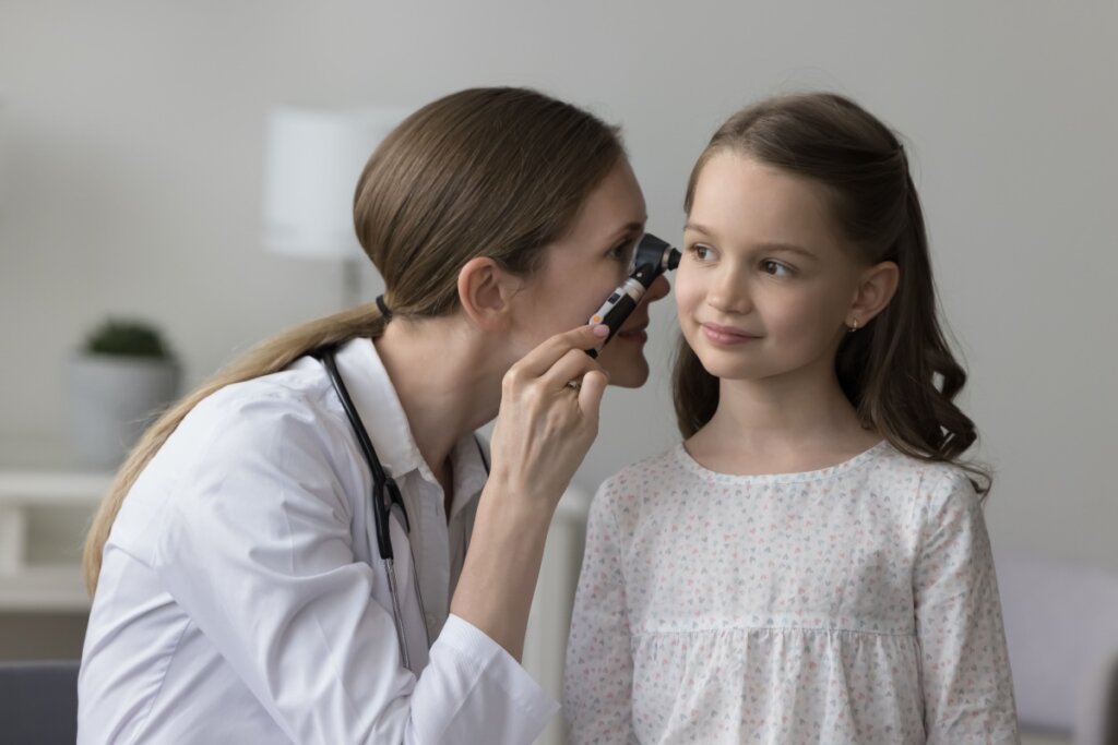 Médica examinando o ouvido de uma menina com um otoscópio durante uma consulta de rotina