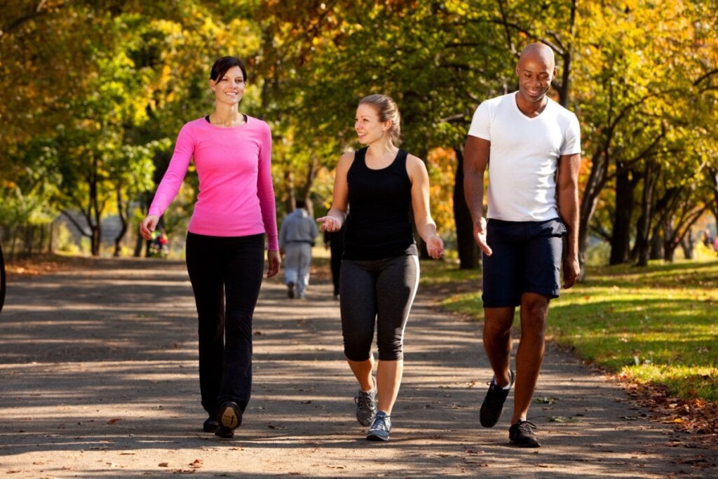 Duas mulheres e um homem caminhando no parque 