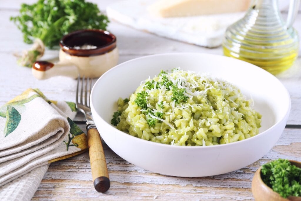 Risoto de queijo em cumbuca branca em cima de mesa de madeira