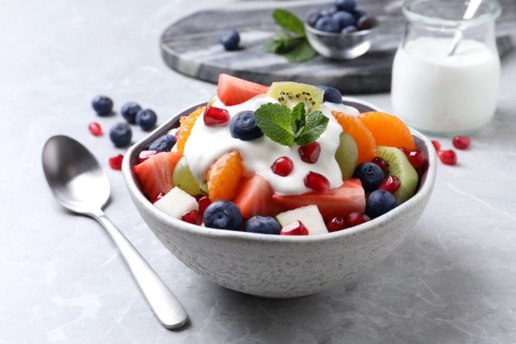 Pote de cerâmica cinza com salada de frutas e iogurte