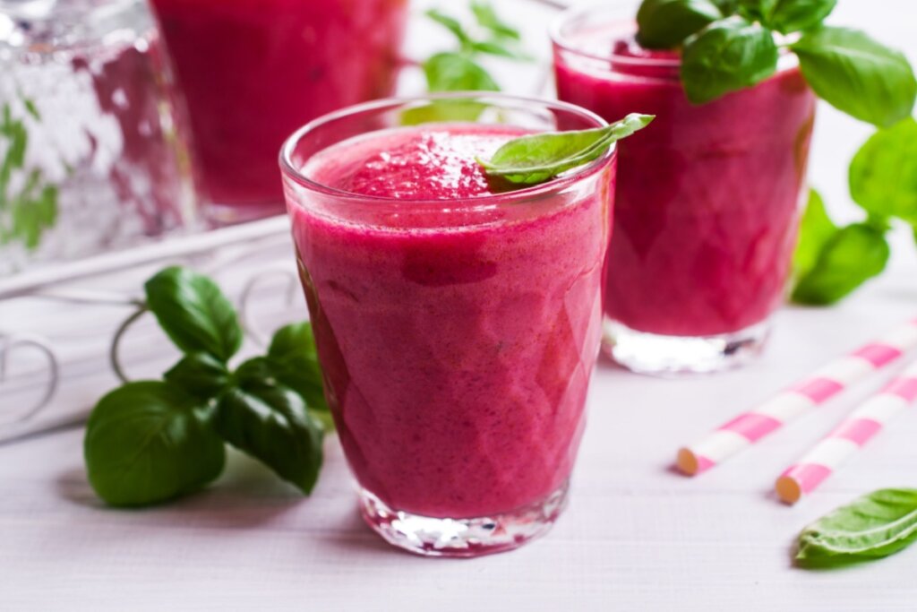 Suco de vermelho de beterraba em copo de vidro com manjericão ao lado