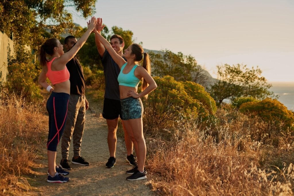 Dois homens e duas mulheres com roupas esportivas comemorando a finalização da prática de trail running