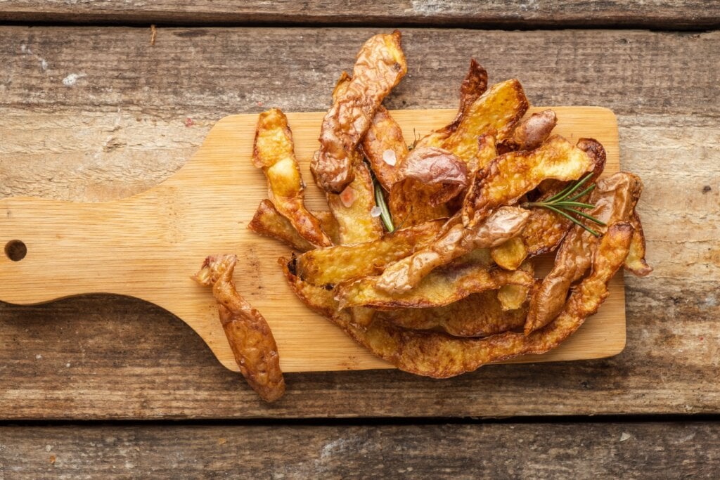 Chips de casca de batata em tábua em cima de mesa de madeira