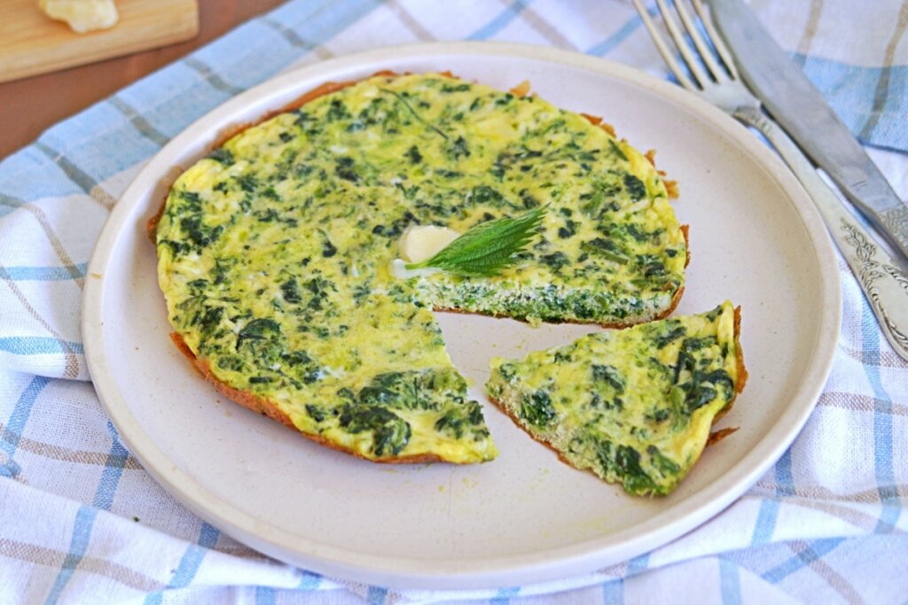 Omelete com folhas de rabanete em cima de um prato branco redondo