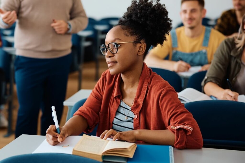 menina estudando em sala com livro e caderno de anotações