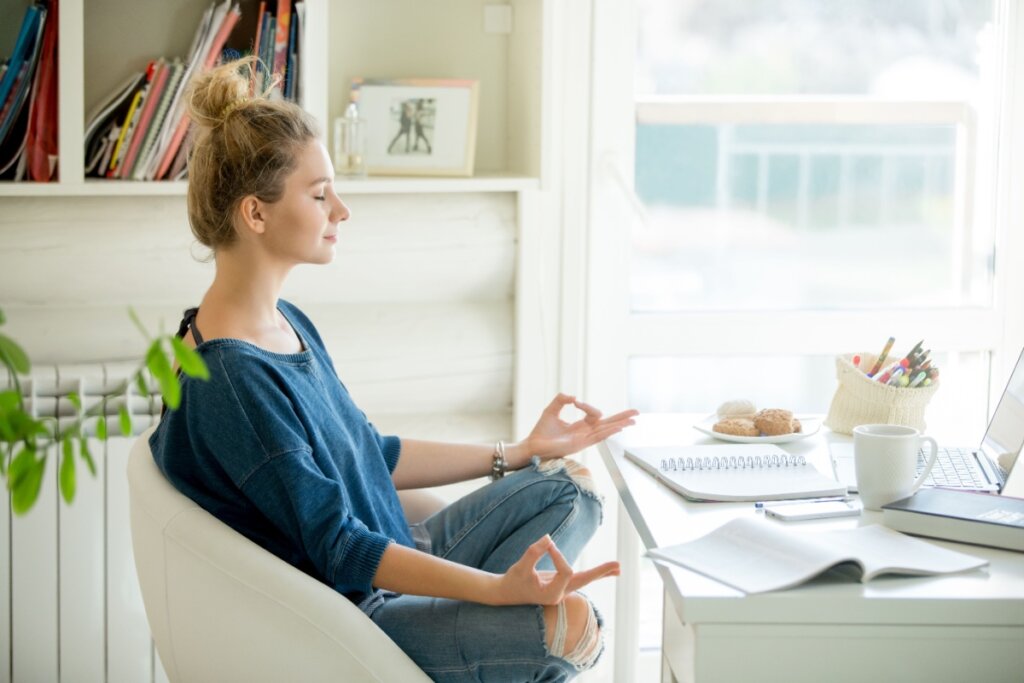 Mulher fazendo yoga frente a uma mesa cheia de papéis