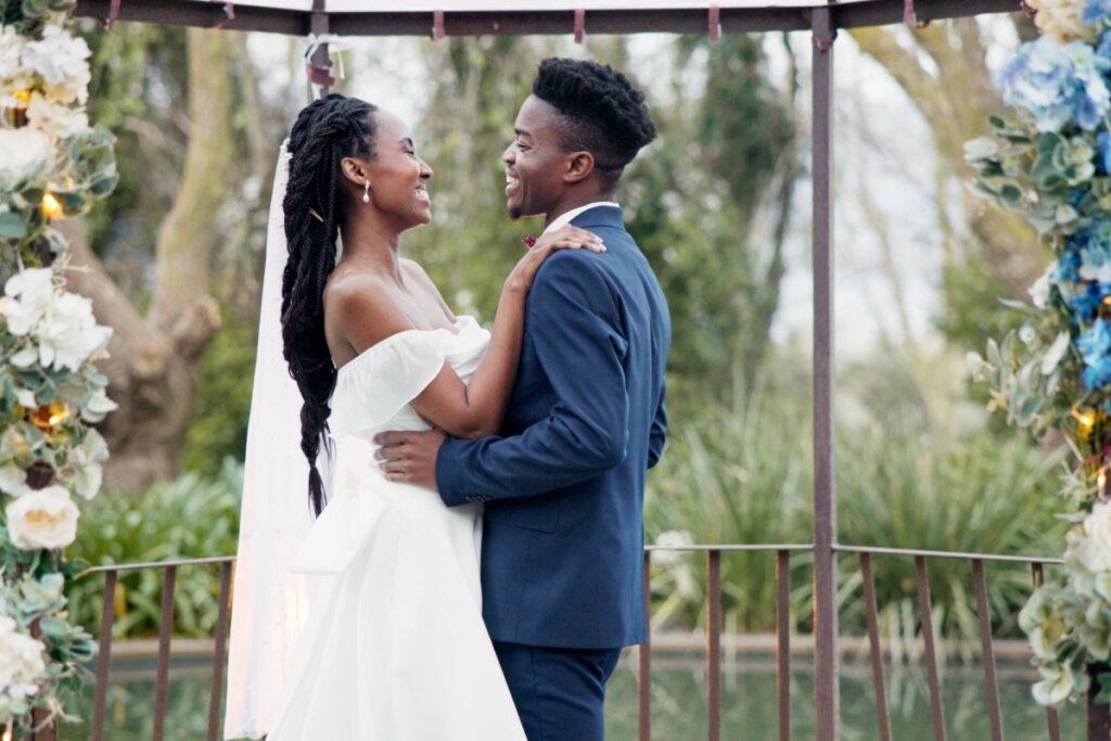 Casal dançando na festa de casamento ao ar livre com flores ao fundo