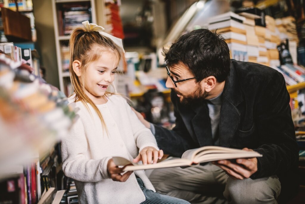 Pai e filha escolhendo livro na livraria