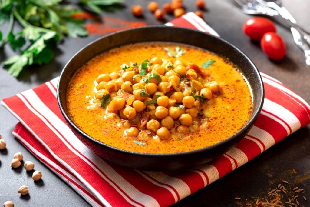 curry de grão-de-bico em pote preto em cima de pano vermelho e branco