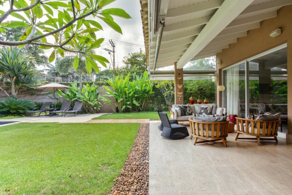 área externa com grama verde e poltronas na varanda em uma casa