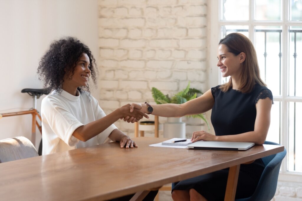 Duas mulheres apertando a mão em entrevista de emprego