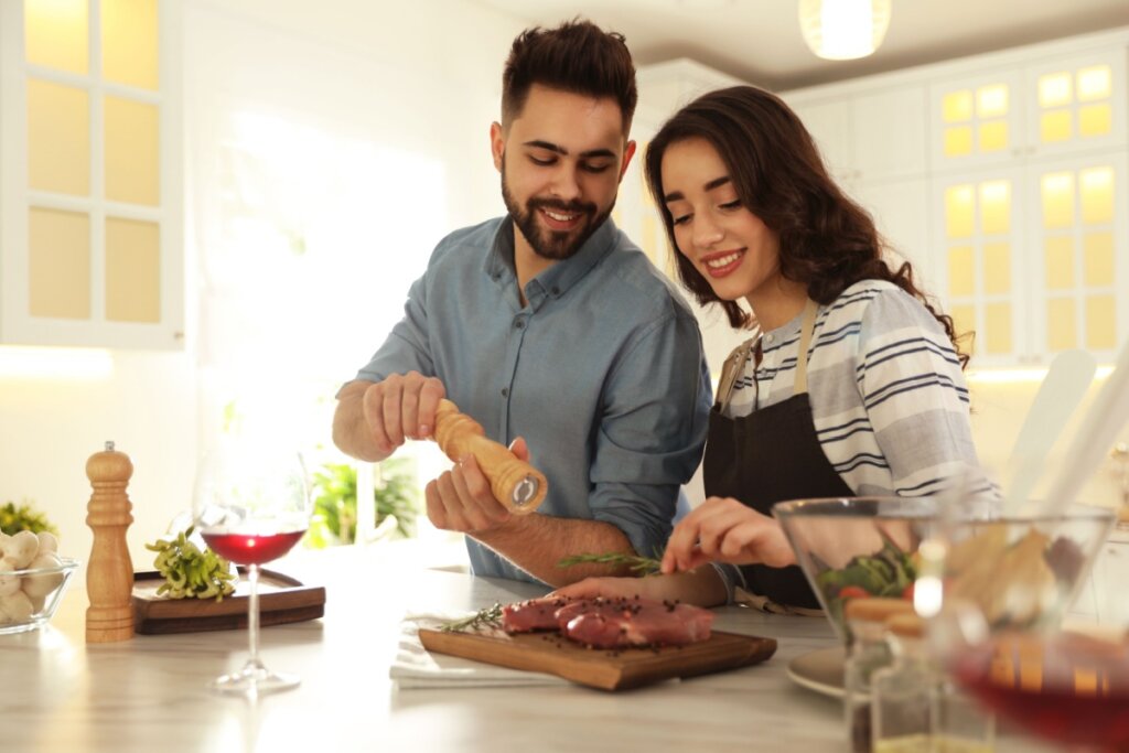 Homem e mulher preparando carne em cozinha