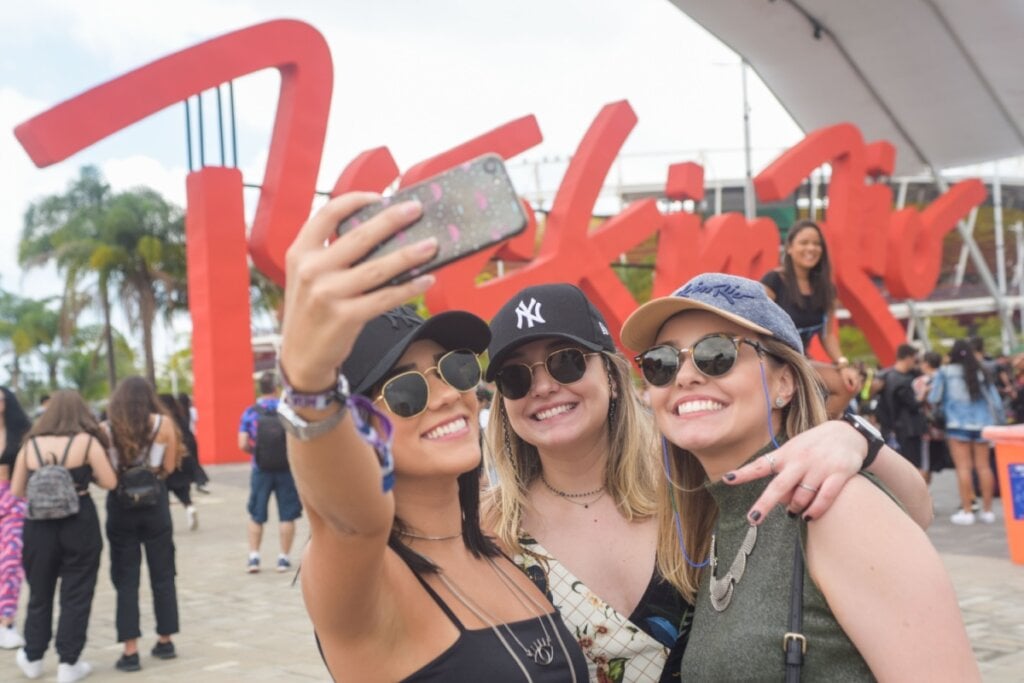 Jovens usando boné e óculos escuros tirando foto no Rock In Rio 