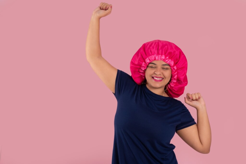 mulher sorrindo com touca de cetim em fundo rosa