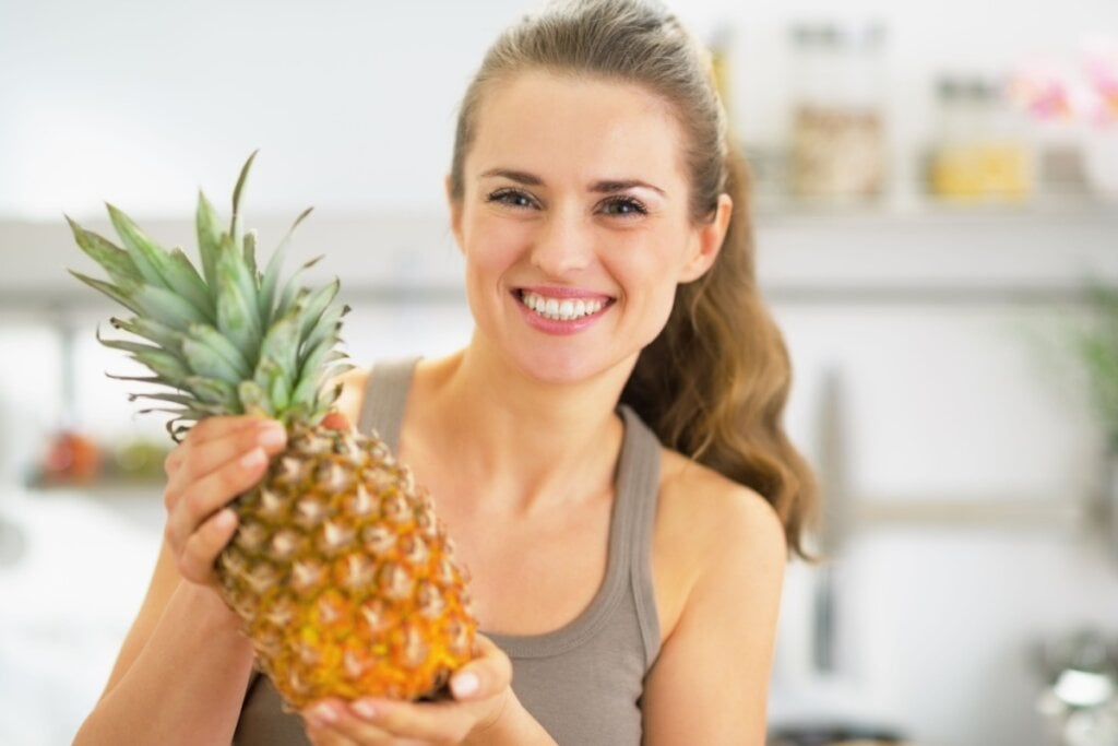 Mulher segurando um abacaxi sorrindo