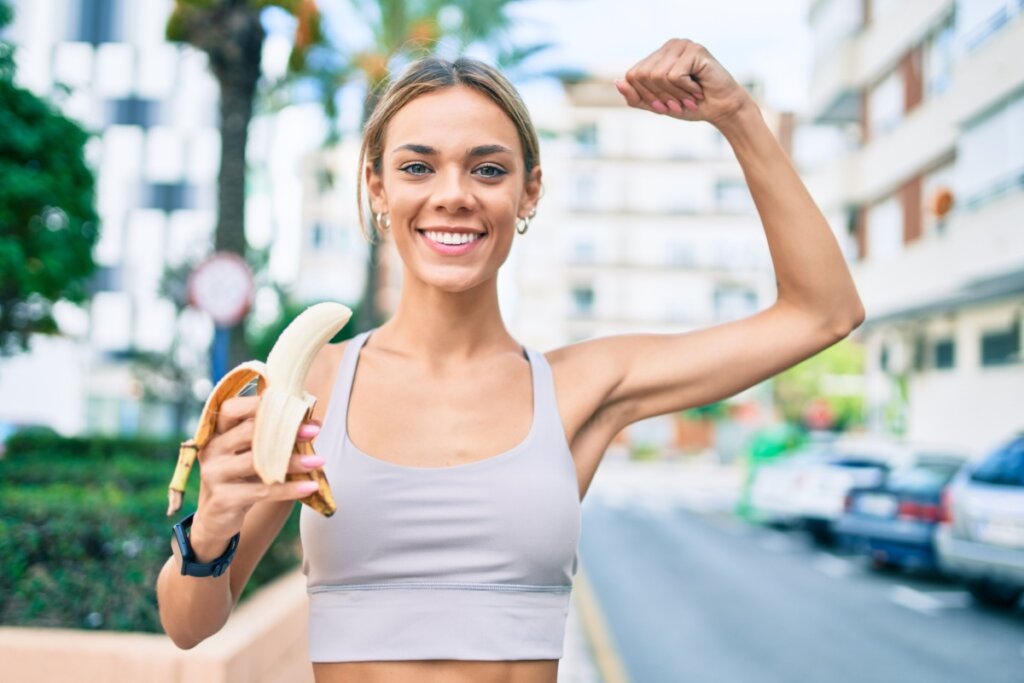 Mulher após fazer exercício ao ar livre segurando uma banana