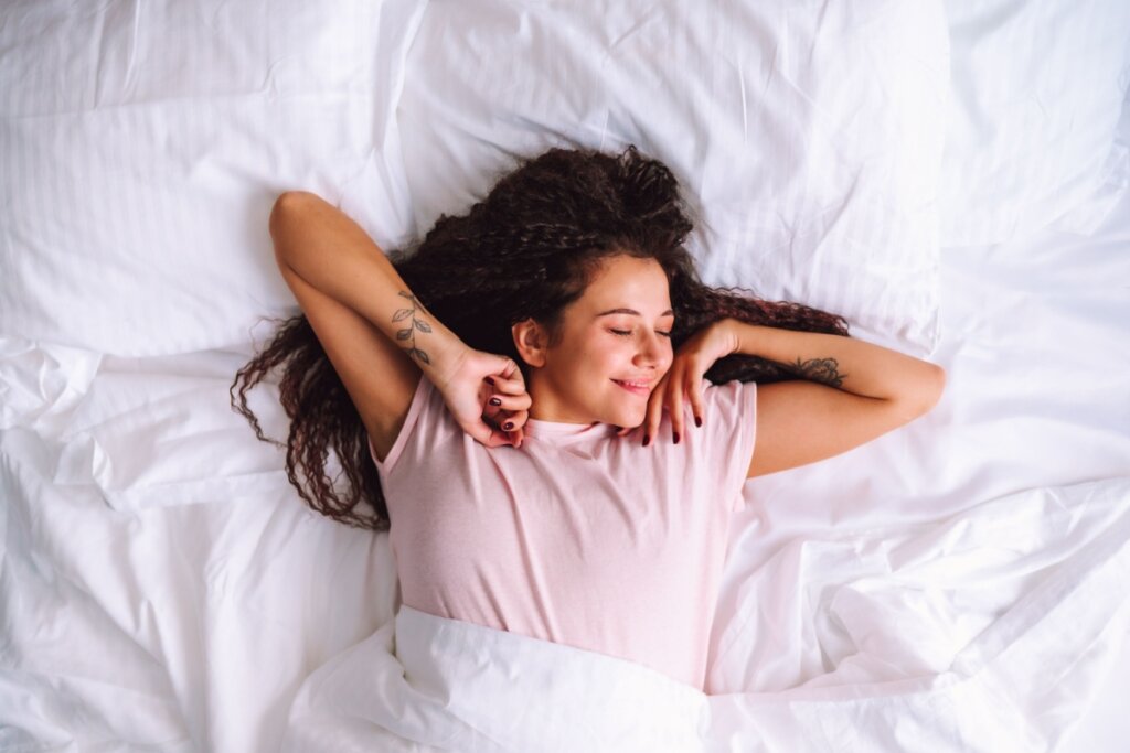 Mulher se espreguiçando na cama com uma expressão feliz