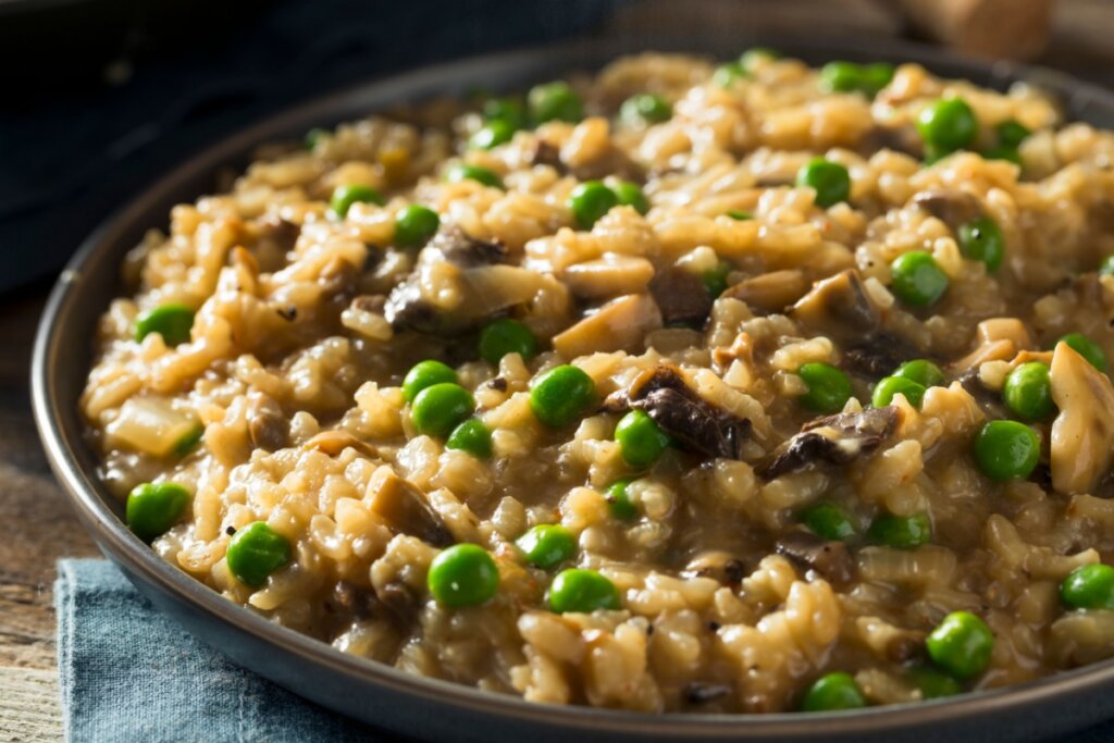 Risoto de cogumelo e ervilha servido em prato de cerâmica preto