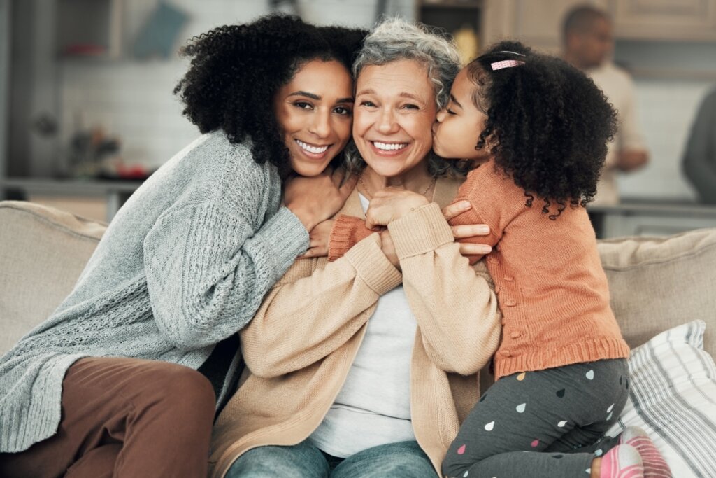 Criança, adulta e idosa juntas abraçadas