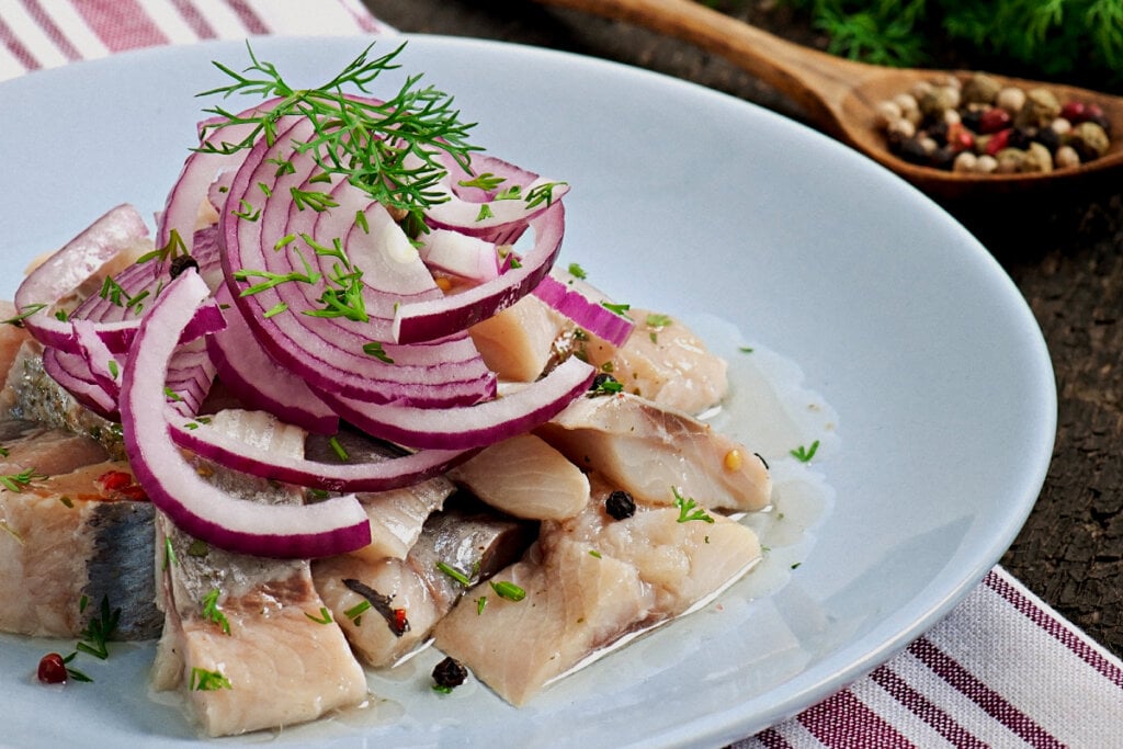 ceviche de peixe cortado com cebola-roxa em prato branco