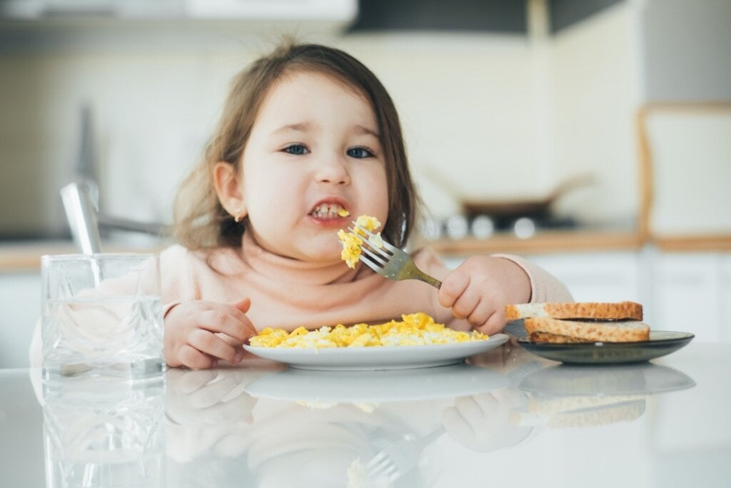 Menina sentada comendo ovo sozinha 