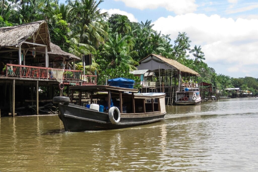 Imagem de barco passando ao lado das casas na Ilha do Combu