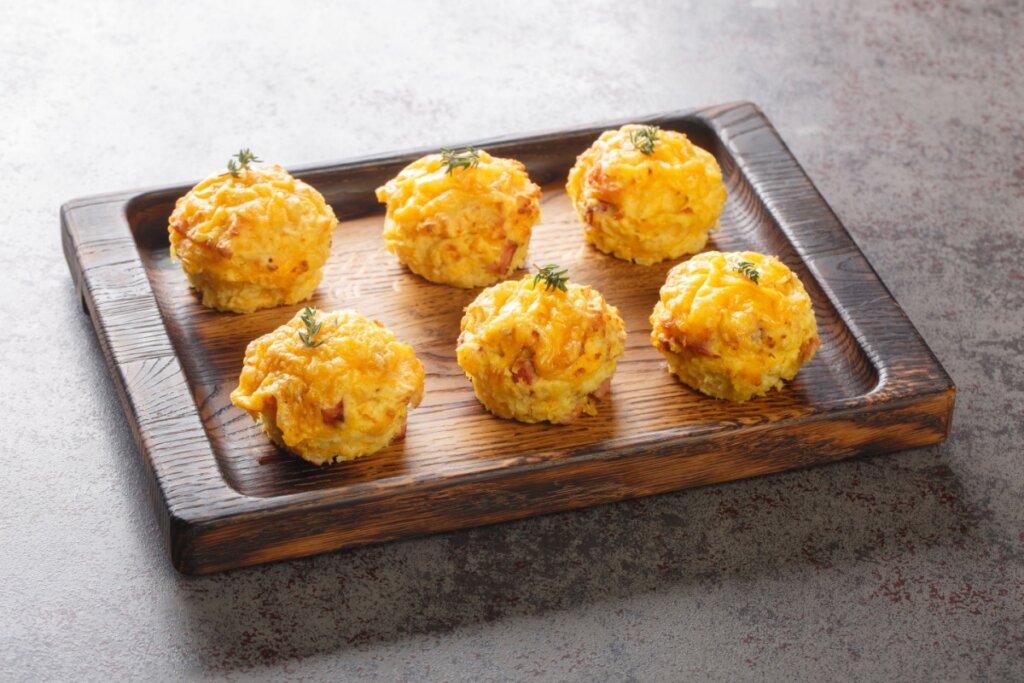 Bolinho de batata e queijo servido em travessa de madeira