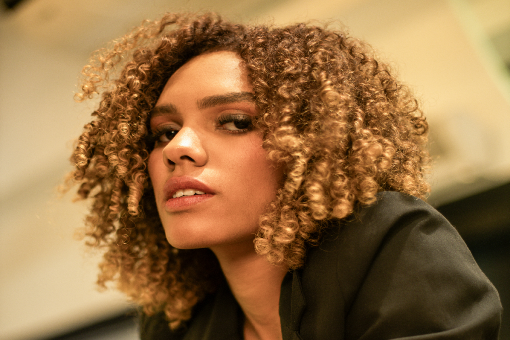 Mulher com o cabelo cacheado pintado em tons de marrom