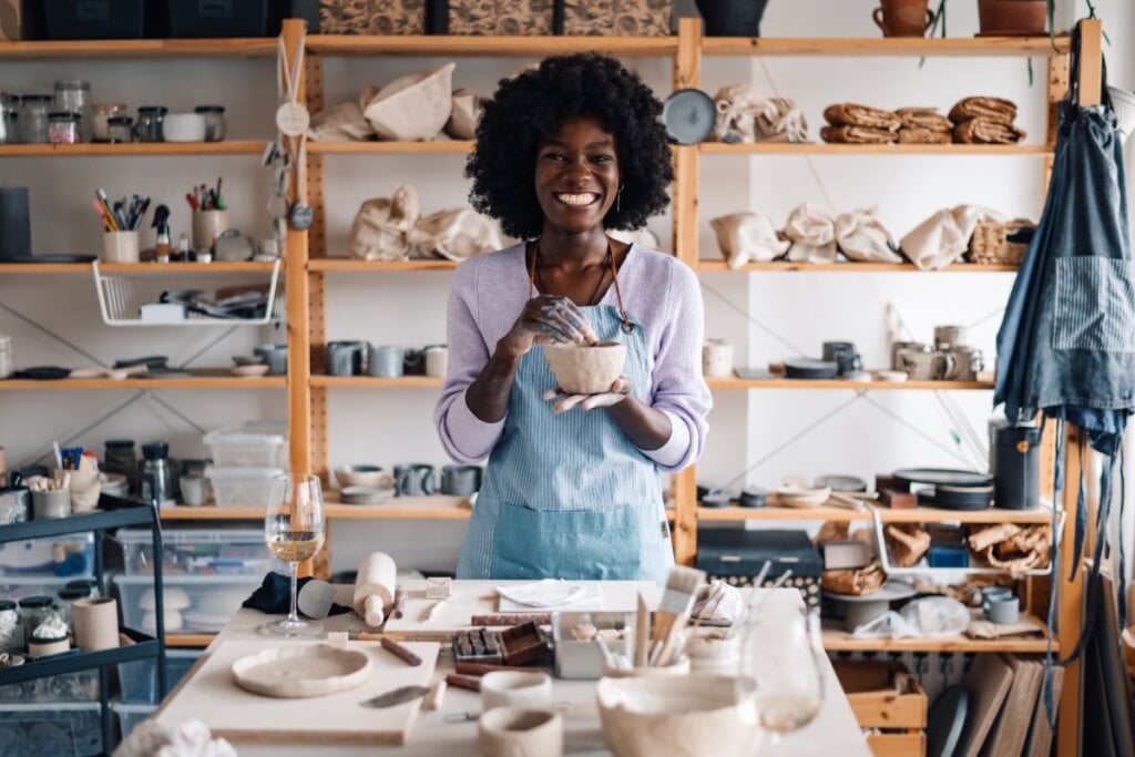 Mulher sorridente modelando uma peça de cerâmica em um estúdio artesanal