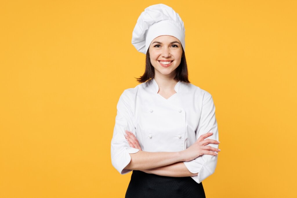 Mulher chef de cozinha de braços cruzados sorrindo