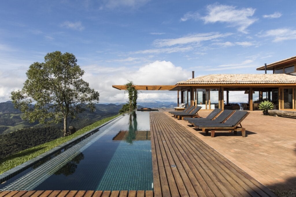 Este deck de madeira cumaru, ao redor da piscina com borda infinita, garante estabilidade e integra o espaço à natureza ao redor (Projeto: Sabella Arquitetura | Imagem: Manuel Sá)