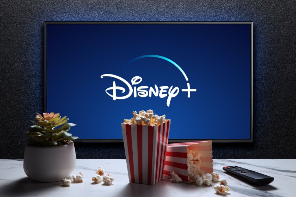 TV com logo do Disney+. potes de pipoca e planta em frente