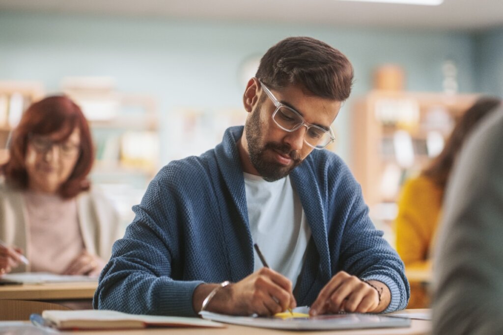 Homem de óculos escrevendo em papel