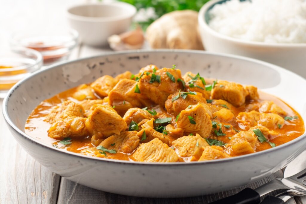 Frango ao curry servido em prato fundo de porcelana