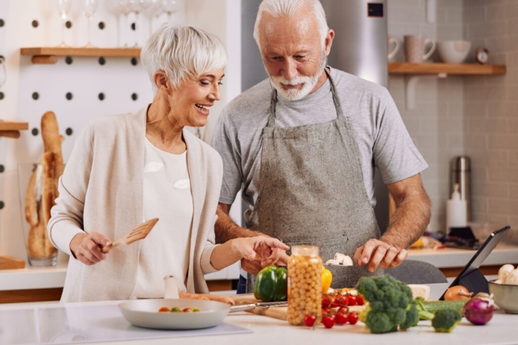 Casal de idosos preparando refeição na cozinha