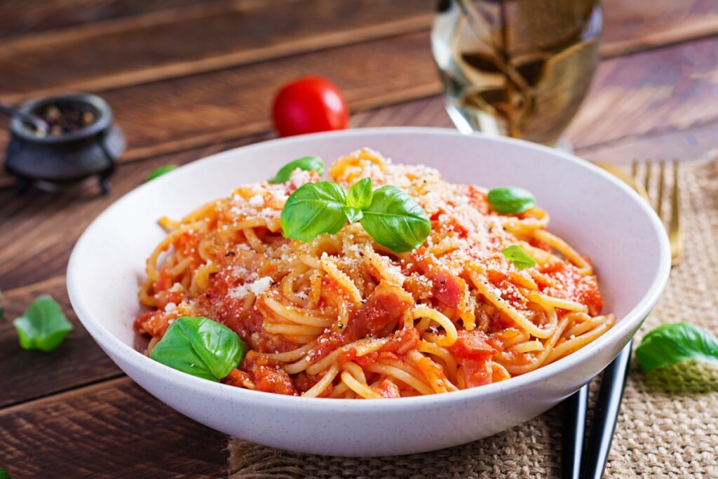 Macarrão com molho de tomate caseiro servido em prato fundo de porcelana branco