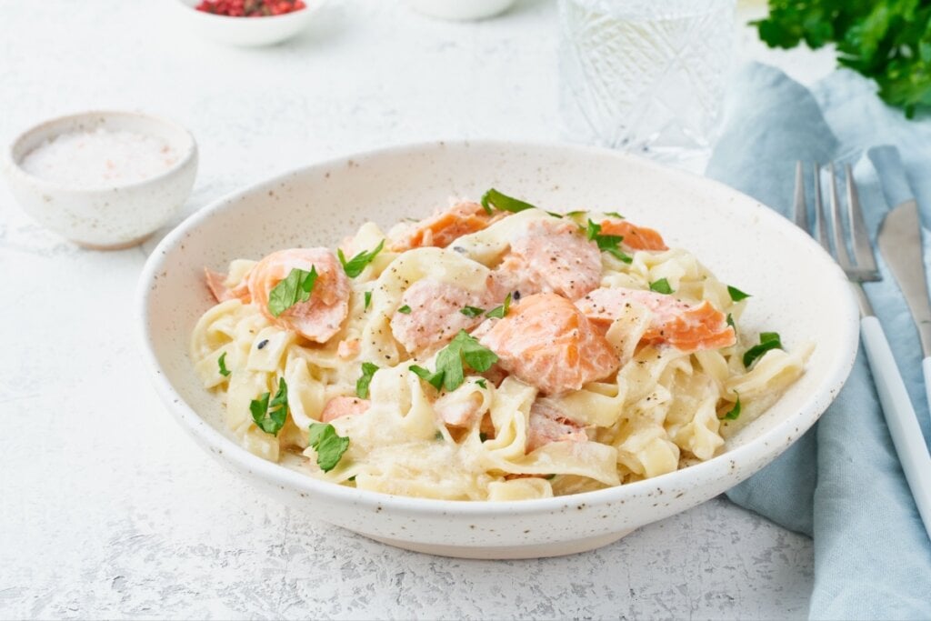 Macarrão com salmão e molho branco servido em prato fundo de porcelana branca