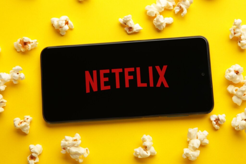 Celular com o logo da Netflix em fundo amarelo com pipocas espalhadas