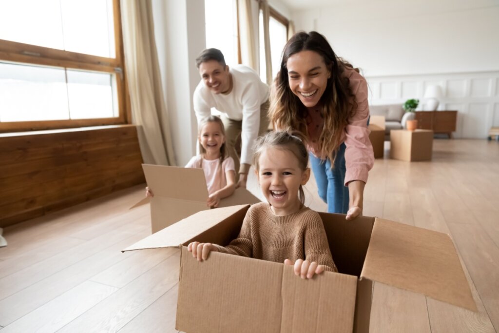 Pais e filhos brincando com os filhos dentro de caixas de papelão