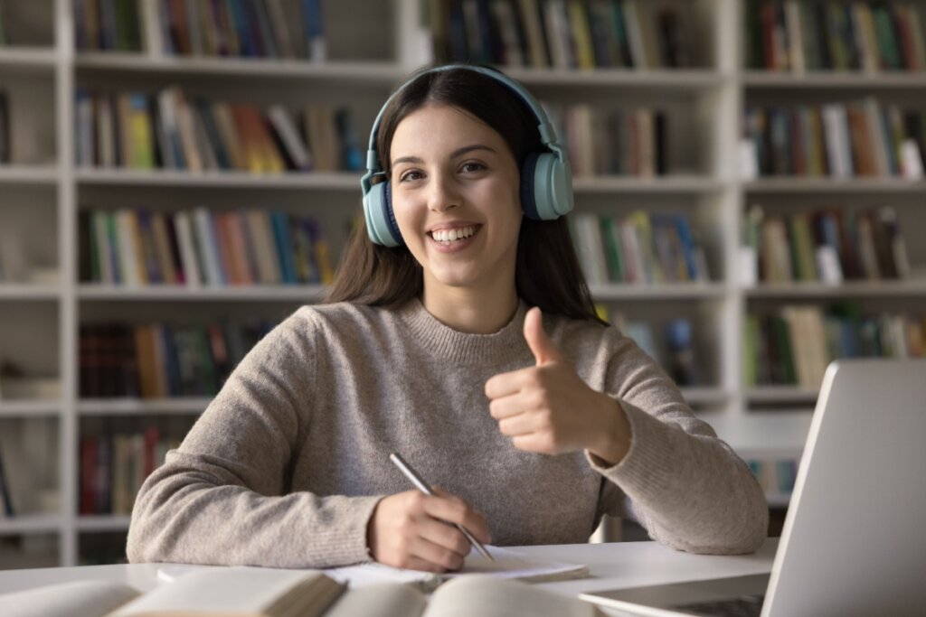 Estudante fazendo redação e "joinha" com a mão