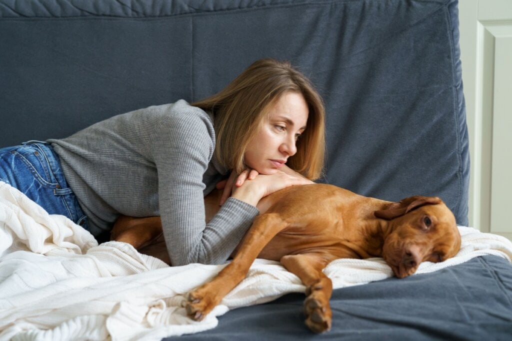 Mulher deitada com cachorro no sofá