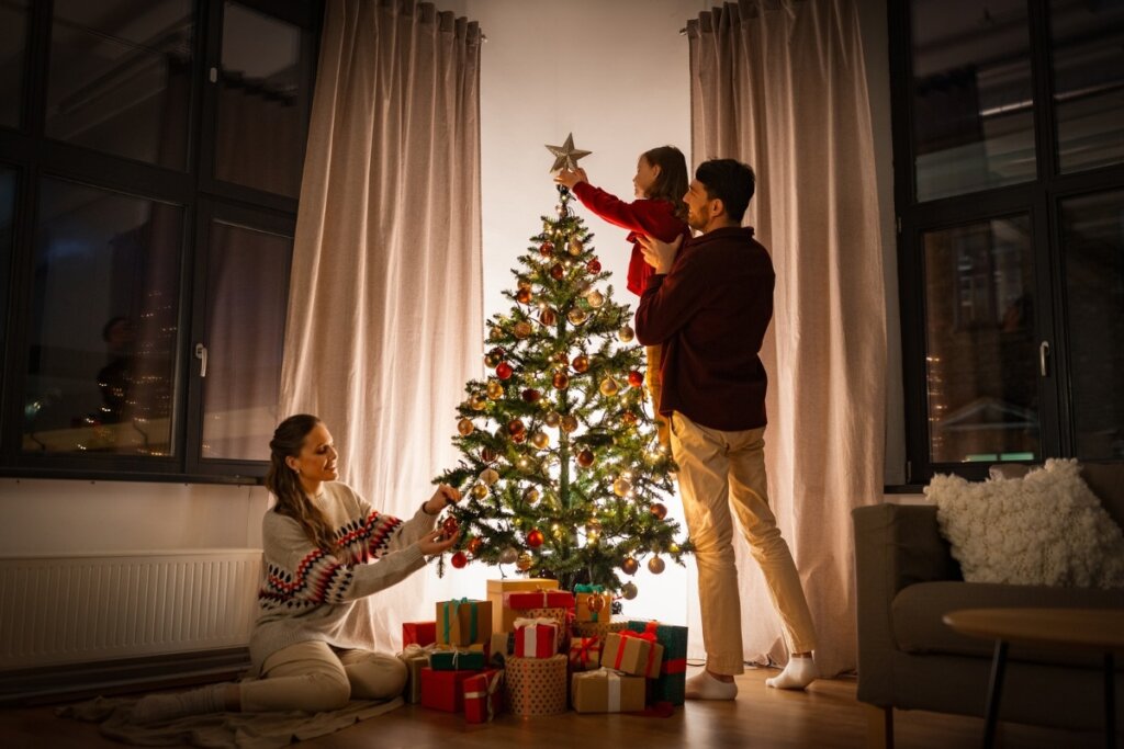 Mulher, homem e uma criança em uma sala de estar montando uma árvore de Natal