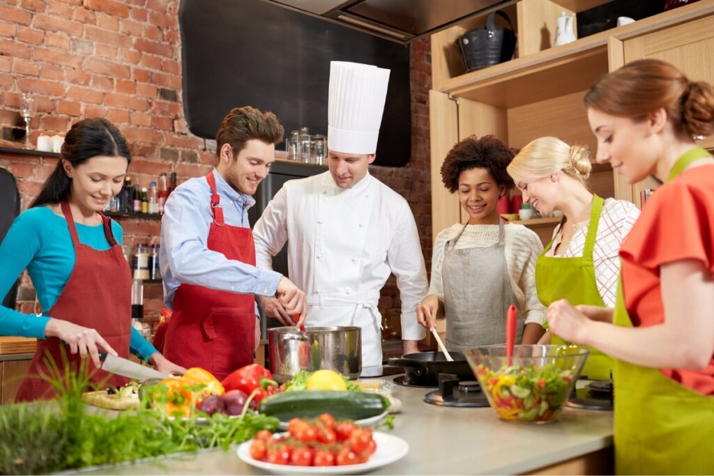 Pessoas em uma cozinha aprendendo a cozinhar com um chefe de cozinha