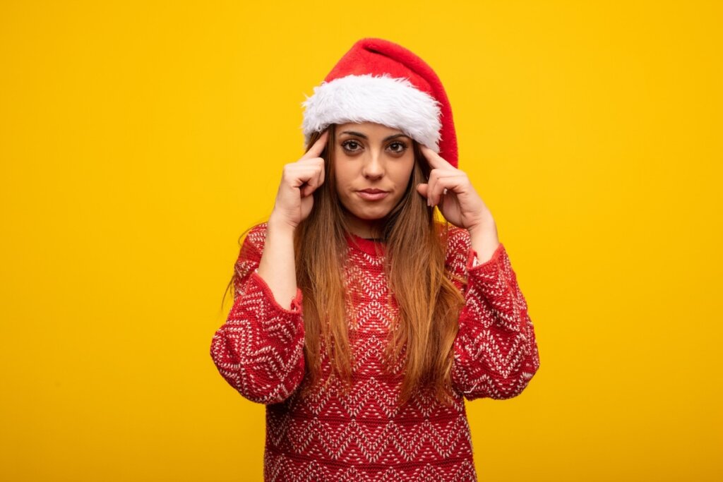 Mulher usando um gorro de natal com dois dedos apontando para a cabeça