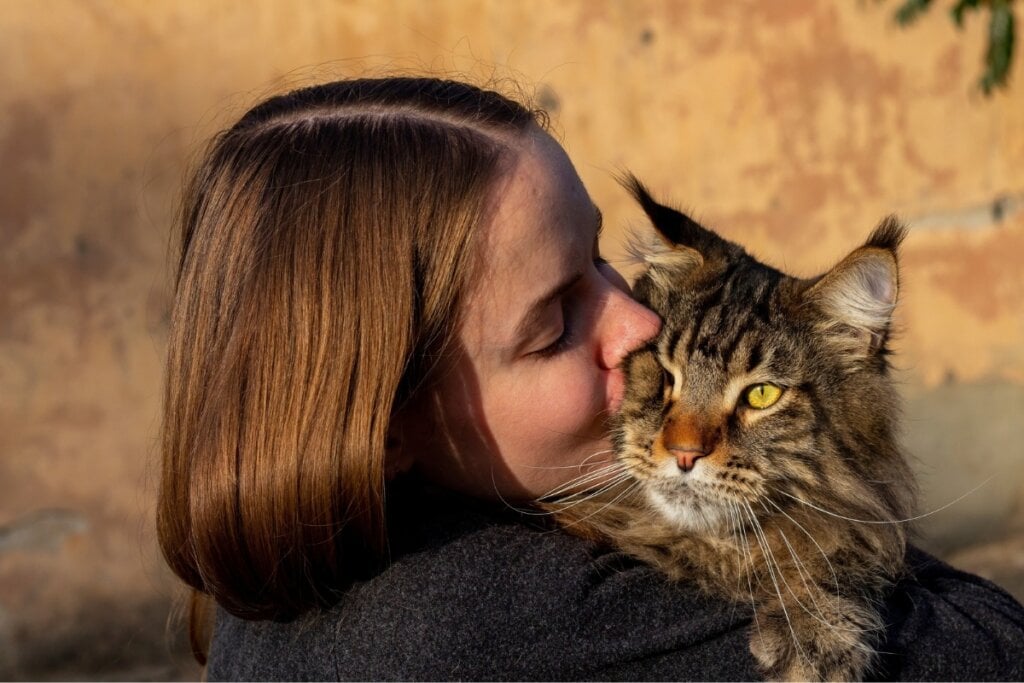 Mulher abraçada e dando beijo em um gato