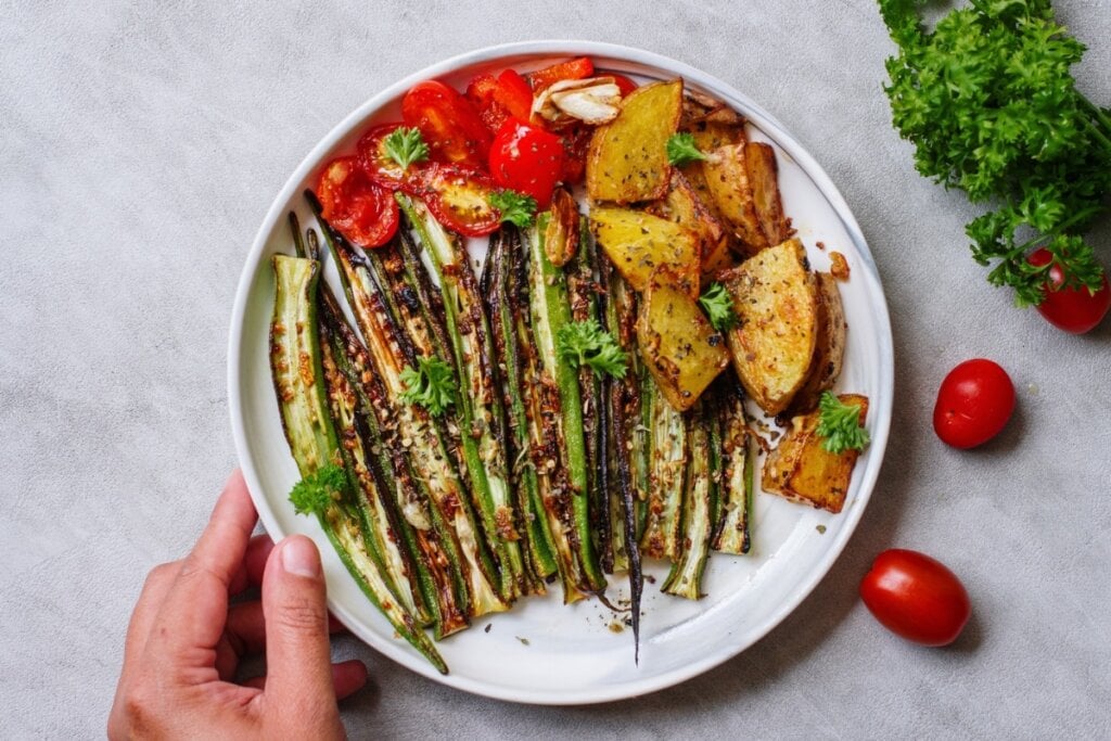 Quiabo grelhado em um prato branco com tomate e batata