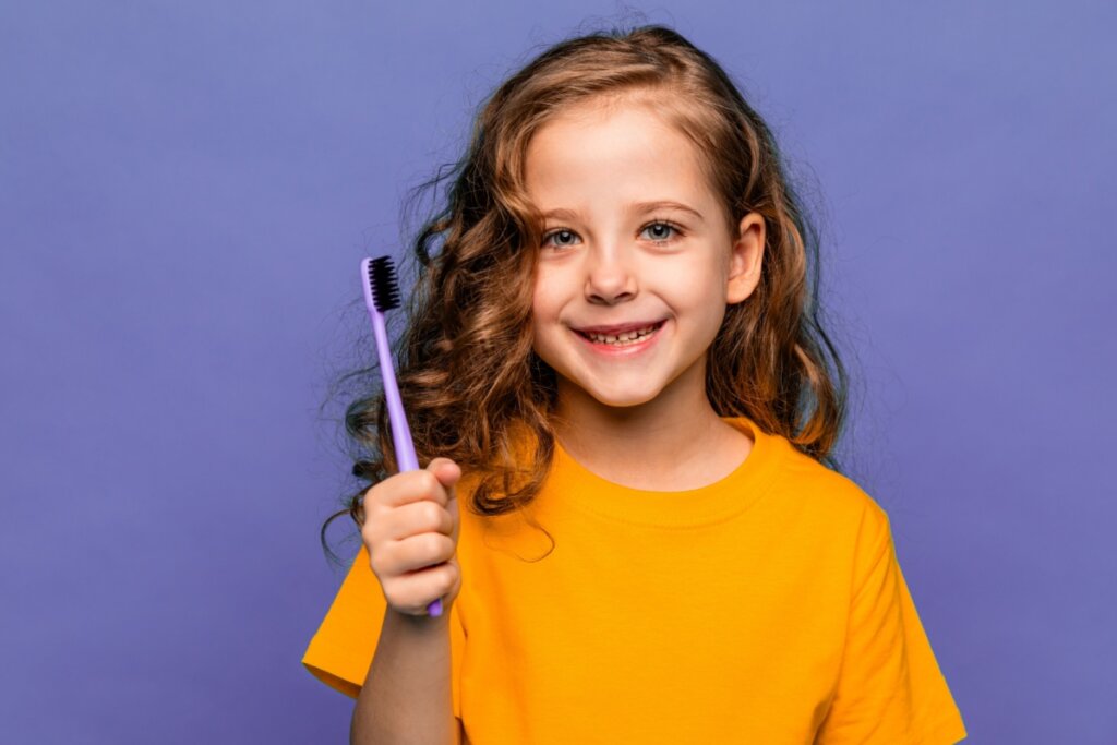 Criança com escova de dente na mão