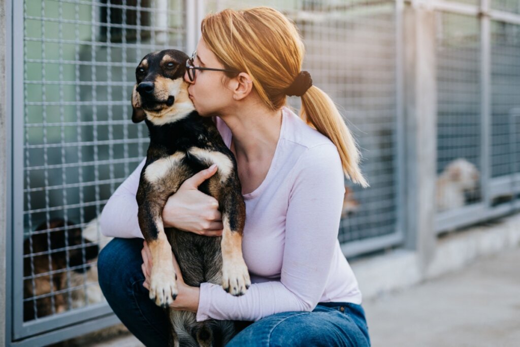 Voluntária de abrigo abraçada com cachorro