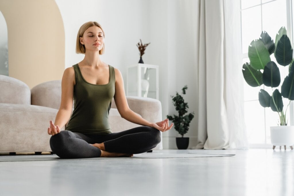 Mulher praticando yoga na sala de casa