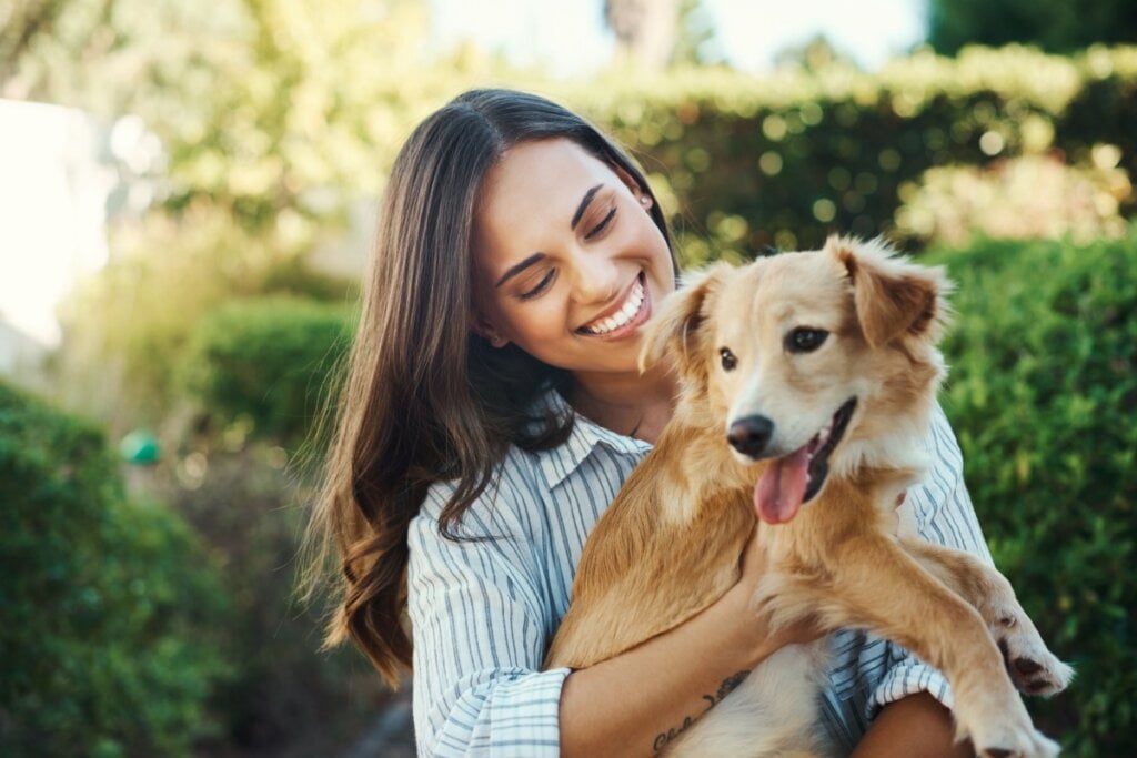 Mulher sorrindo e segurando cachorro no colo